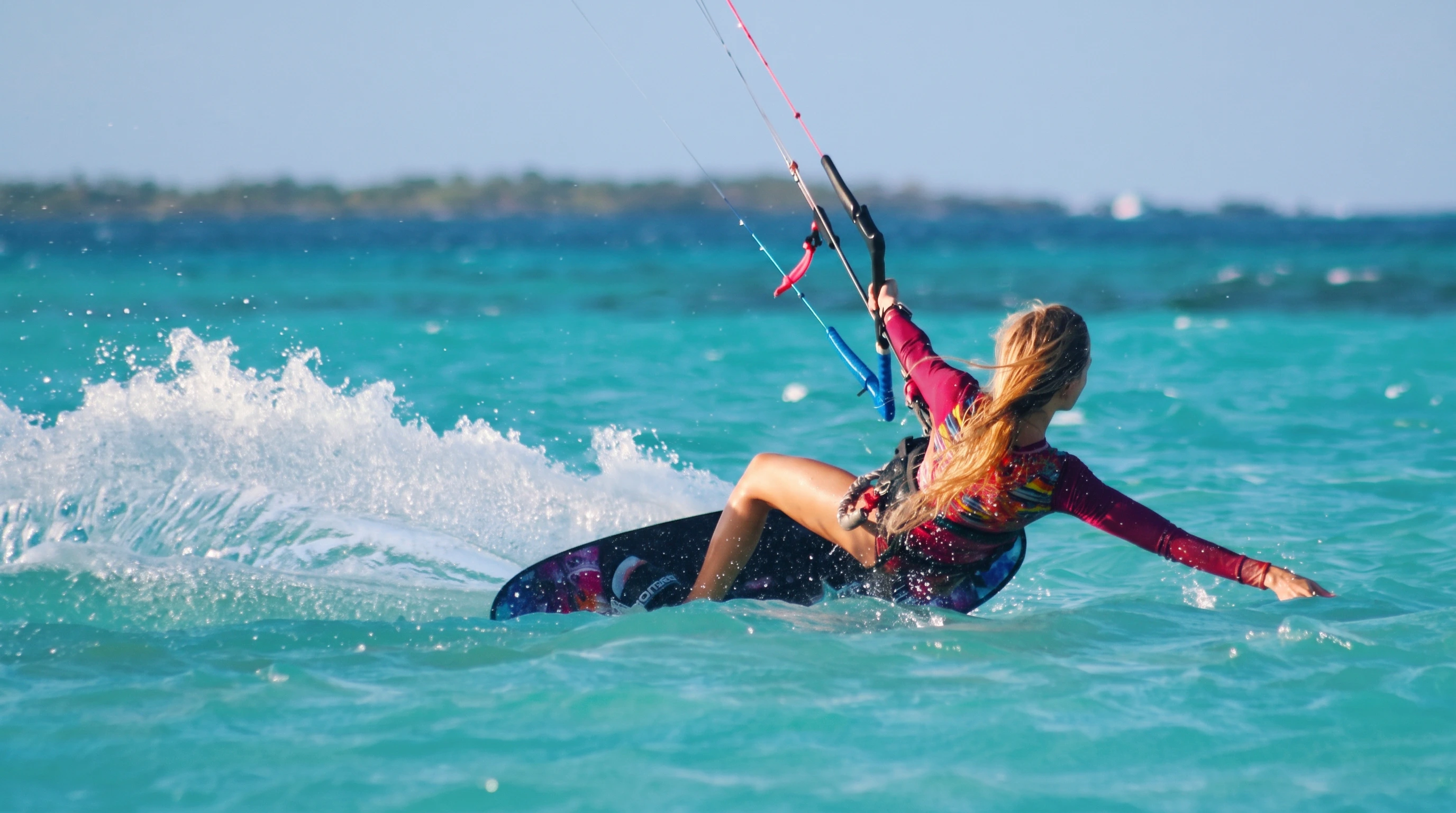 Nomad Okam-Pro, the next generation of the Ocean Rodeo Mako, rider carving hard through turquoise water, spray thrown high