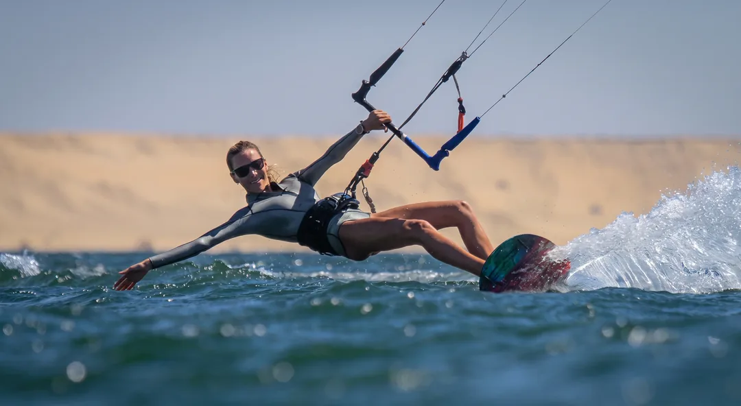 Nomad Okam-Pro rider holding a confident edge, carving hard in front of the dunes