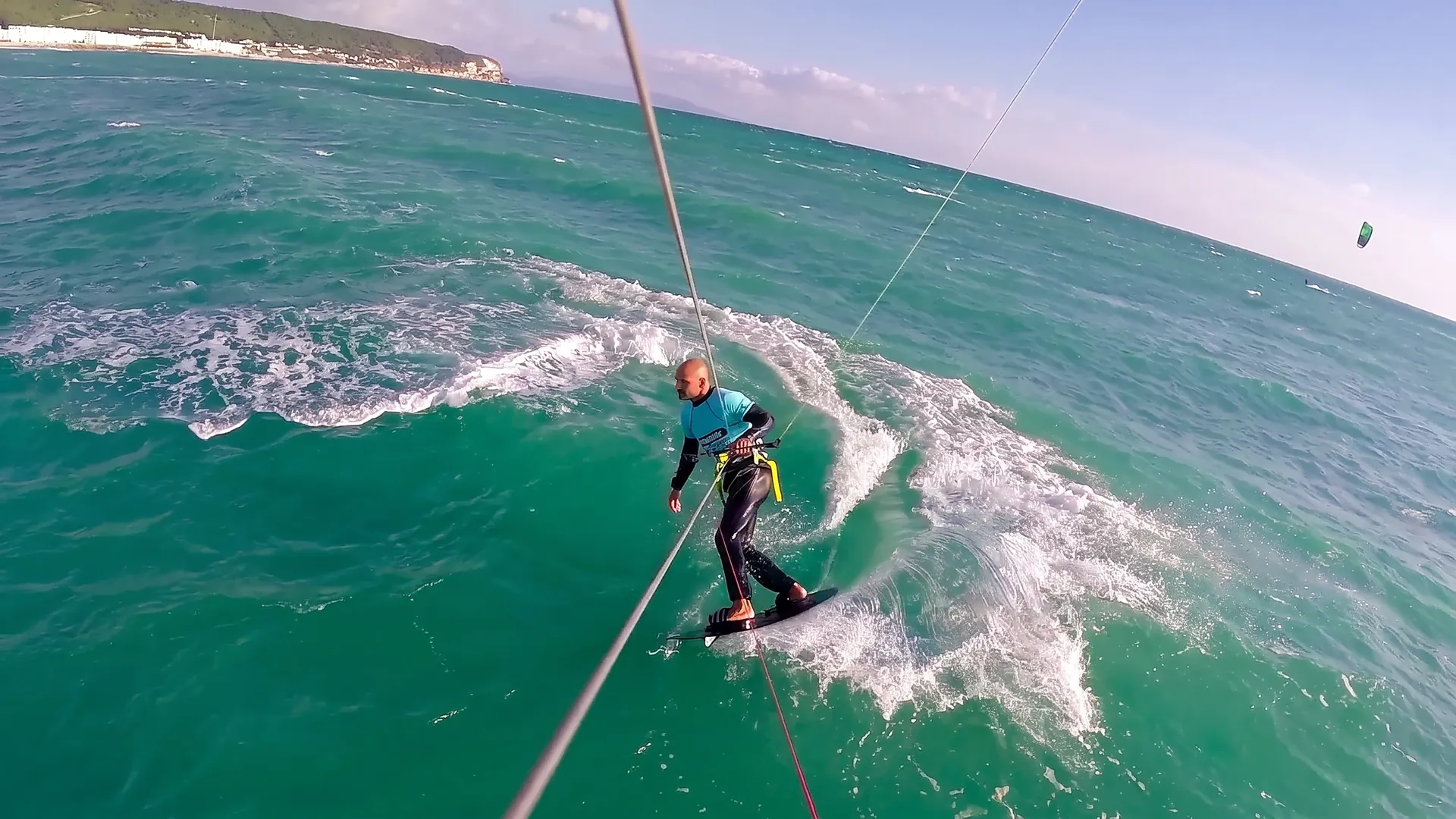 Nomad Okam-Pro, the Ocean Rodeo Mako successor, rider carving cleanly through green chop, wide angle GoPro shot