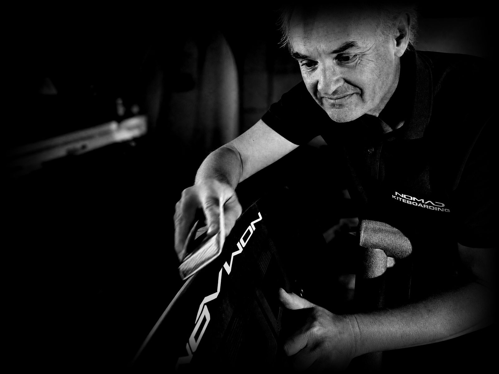 Simon Harvey, Nomad founder and shaper, hand-finishing a Nomad twin-tip in the workshop