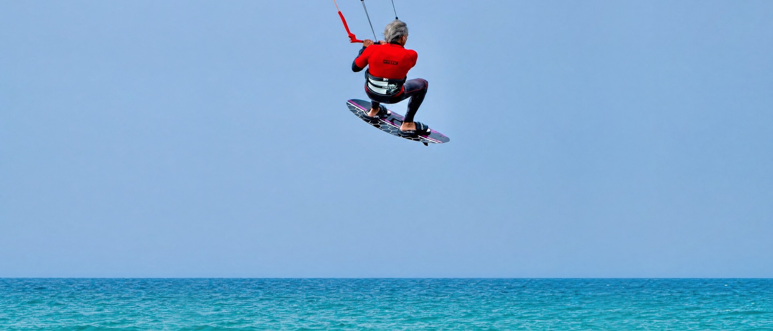 Nomad rider boosting a big air jump on the Wave Twin-Tip against a clear blue sky